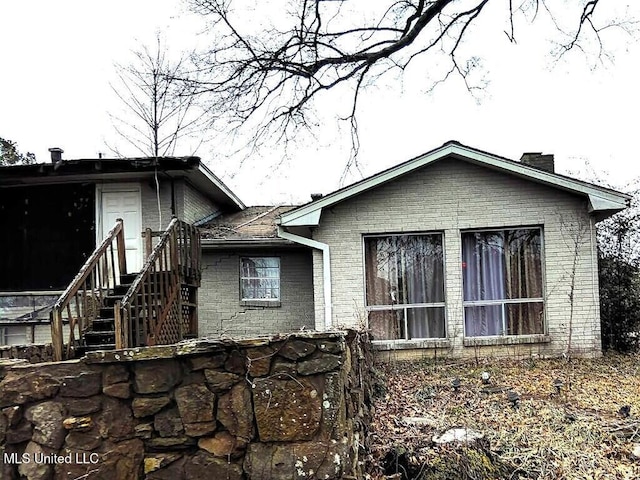 back of property featuring brick siding and a chimney