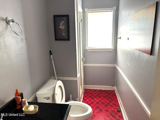 bathroom featuring toilet, baseboards, and vanity