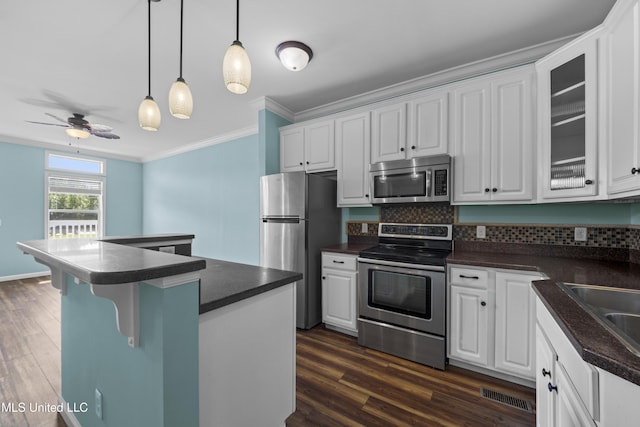 1515 E Beach Blvd Unit 114, Pass Christian, MS 39571 - kitchen featuring appliances with stainless steel finishes, dark countertops, crown molding, and white cabinets