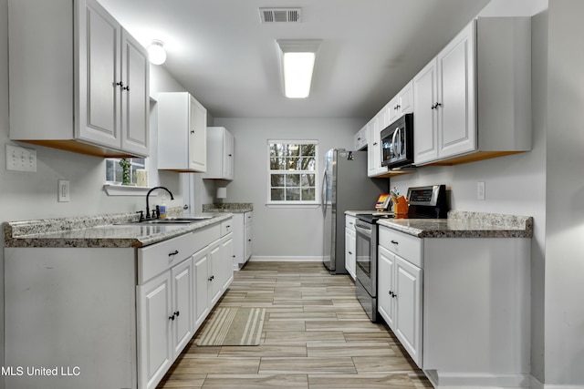 kitchen featuring white cabinetry, stainless steel appliances, sink, and light stone counters