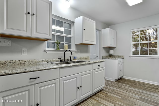 kitchen with white cabinetry, sink, and light wood-type flooring