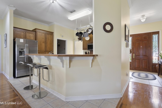 311 Pinecrest Blvd, Long Beach, MS 39560 - kitchen with appliances with stainless steel finishes, a kitchen bar, light tile patterned flooring, ornamental molding, and baseboards