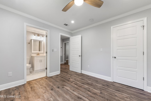 unfurnished bedroom featuring ensuite bath, ceiling fan, dark wood-type flooring, sink, and crown molding