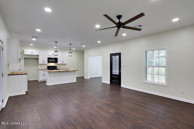 unfurnished living room featuring dark wood-type flooring and ceiling fan