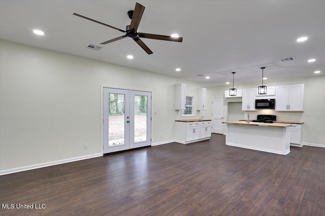 kitchen featuring dark wood-type flooring, a center island, black appliances, white cabinetry, and decorative light fixtures