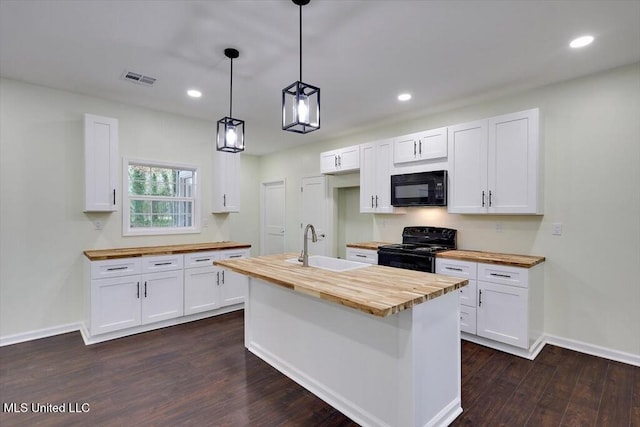 kitchen featuring dark hardwood / wood-style flooring, butcher block counters, a center island with sink, black appliances, and white cabinetry