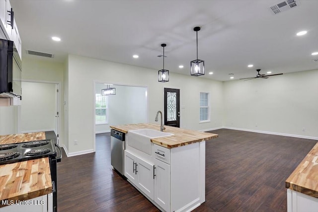 kitchen with pendant lighting, a kitchen island with sink, butcher block counters, and white cabinets