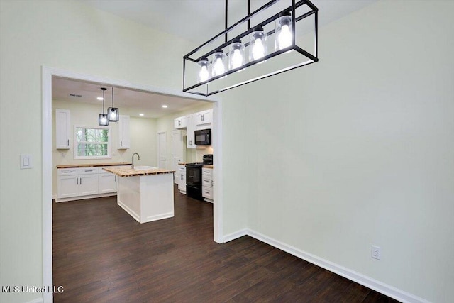 kitchen with dark hardwood / wood-style flooring, butcher block counters, black appliances, an island with sink, and white cabinetry