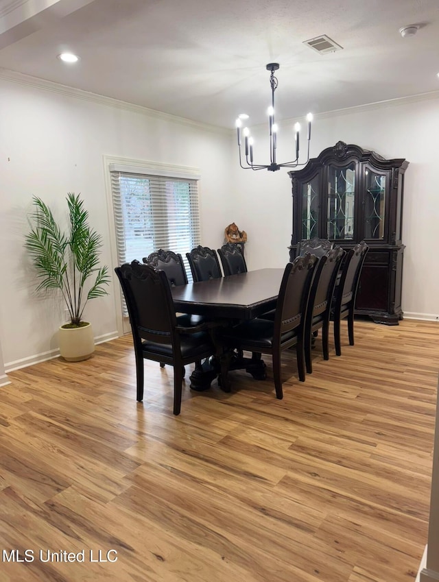 dining room with ornamental molding, an inviting chandelier, and light hardwood / wood-style flooring