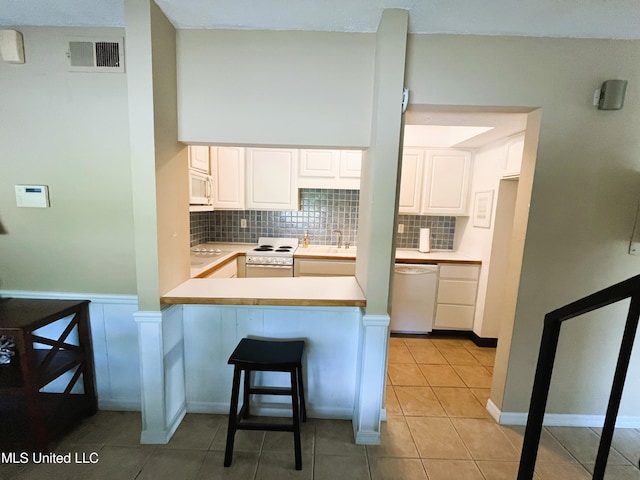 2501 Gulf Ave Unit 22, Gulfport, MS 39501 - kitchen featuring white appliances, tasteful backsplash, a peninsula, and white cabinets