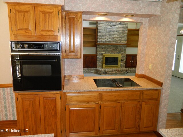 kitchen featuring hardwood / wood-style flooring, black appliances, and a fireplace