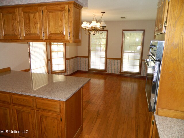 kitchen with hardwood / wood-style floors, hanging light fixtures, an inviting chandelier, and oven