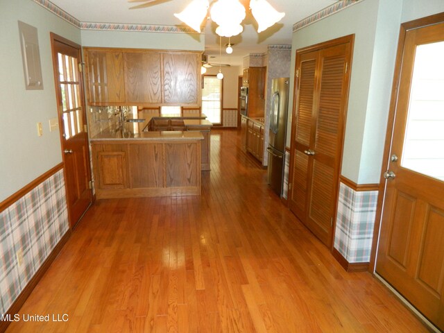 kitchen with ceiling fan, stainless steel refrigerator, kitchen peninsula, and hardwood / wood-style floors