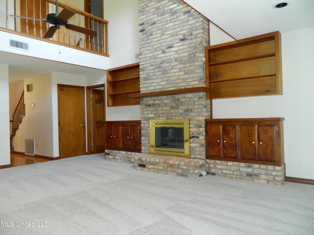 unfurnished living room featuring ceiling fan, carpet flooring, a high ceiling, and a fireplace