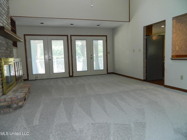 unfurnished living room featuring french doors, a fireplace, and carpet flooring