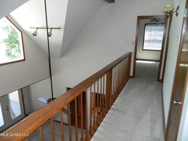 hall featuring lofted ceiling and light carpet