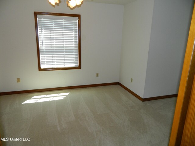 empty room featuring a notable chandelier and light carpet