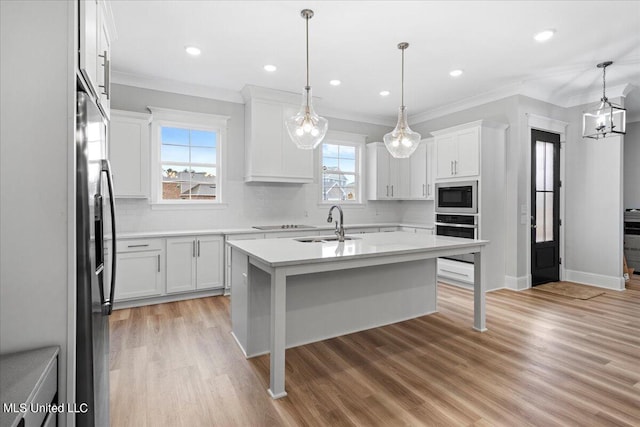 kitchen with a wealth of natural light, appliances with stainless steel finishes, and white cabinetry