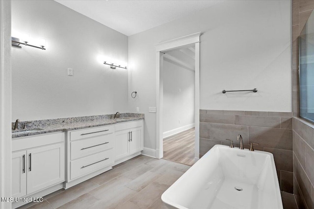 bathroom featuring vanity, a tub to relax in, tile walls, and hardwood / wood-style floors