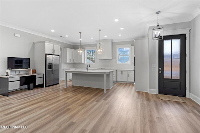 kitchen featuring light wood-type flooring, stainless steel fridge with ice dispenser, and pendant lighting