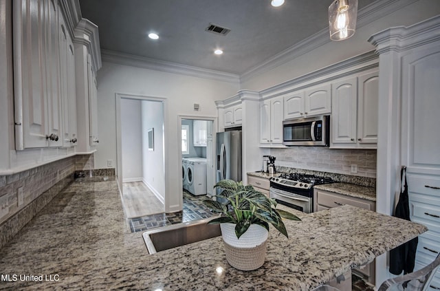 312 Faith Way, Brandon, MS 39042 - kitchen featuring appliances with stainless steel finishes, washing machine and clothes dryer, light stone countertops, decorative backsplash, and wood finished floors