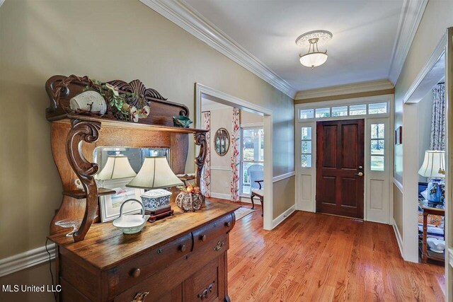 foyer featuring baseboards, ornamental molding, and light wood-type flooring