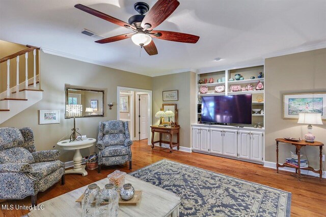 living room with crown molding, stairway, a ceiling fan, and visible vents