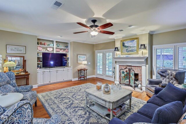 living area with visible vents, ornamental molding, ceiling fan, and wood finished floors