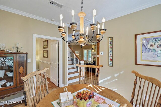 dining space with visible vents, crown molding, wood finished floors, stairway, and a chandelier