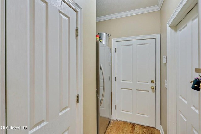 washroom featuring ornamental molding, laundry area, and light wood-type flooring