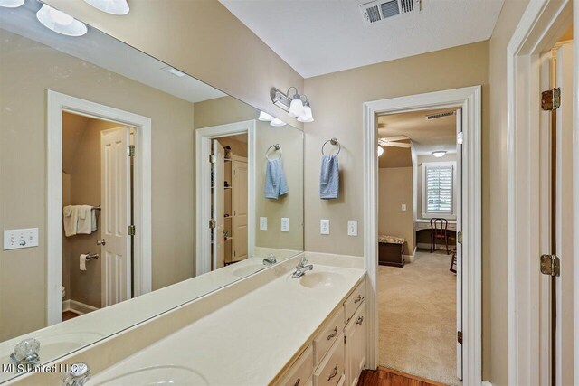 full bath with a sink, baseboards, double vanity, and visible vents