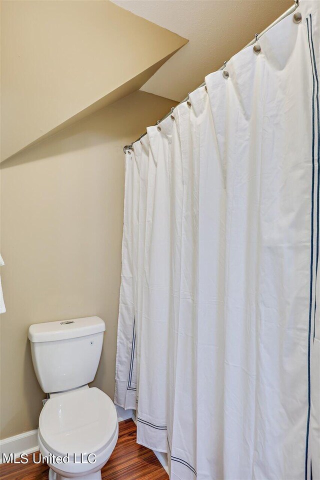 full bath with toilet, baseboards, and wood finished floors