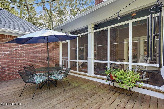 wooden deck featuring outdoor dining space and a sunroom