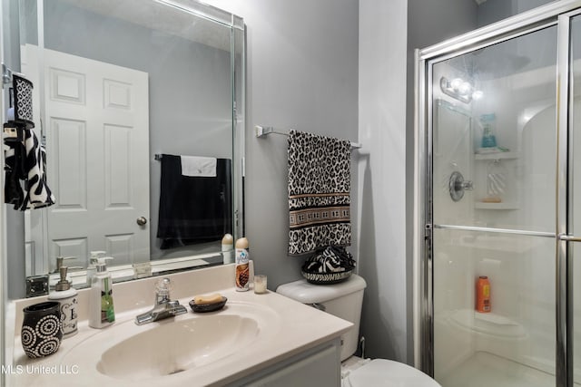 bathroom with toilet, vanity, and a shower with door