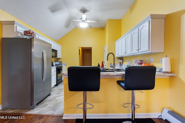 kitchen featuring black appliances, kitchen peninsula, a kitchen breakfast bar, and white cabinets