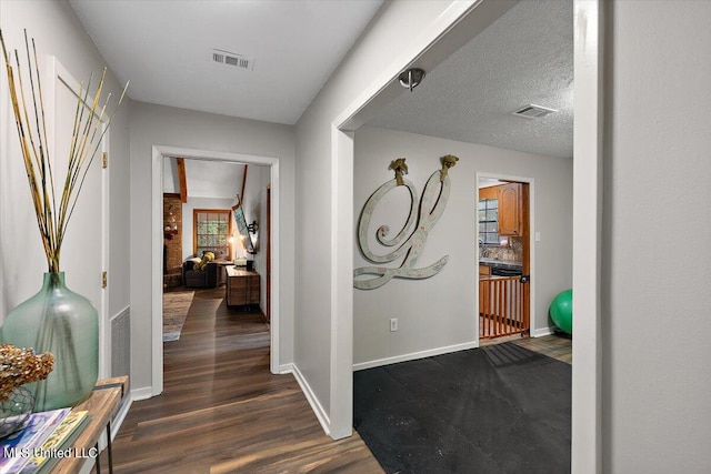 hall featuring a textured ceiling and dark hardwood / wood-style floors