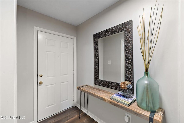 doorway with baseboards and dark wood-type flooring