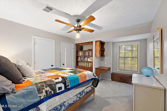 carpeted bedroom with ceiling fan and a textured ceiling