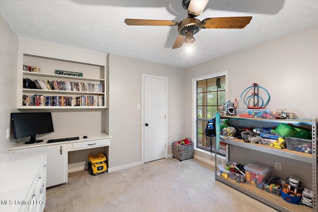home office with ceiling fan, built in study area, light colored carpet, and baseboards