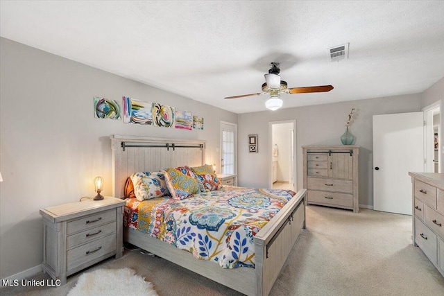 bedroom with ensuite bath, light carpet, a textured ceiling, and ceiling fan