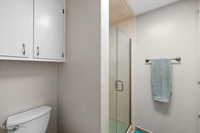 bathroom with a shower with shower door and toilet