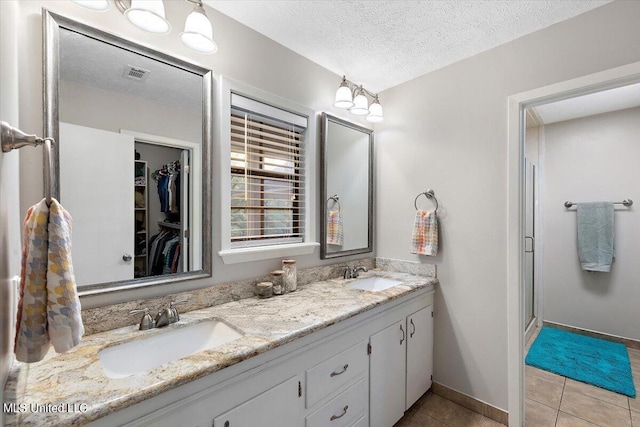 bathroom featuring tile patterned flooring, a sink, double vanity, and visible vents