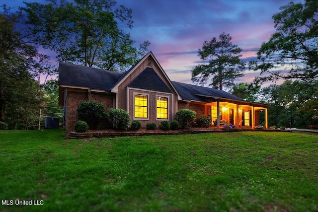 view of front of house with central air condition unit and a lawn