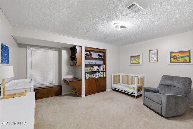 sitting room with a textured ceiling, visible vents, carpet floors, and baseboards