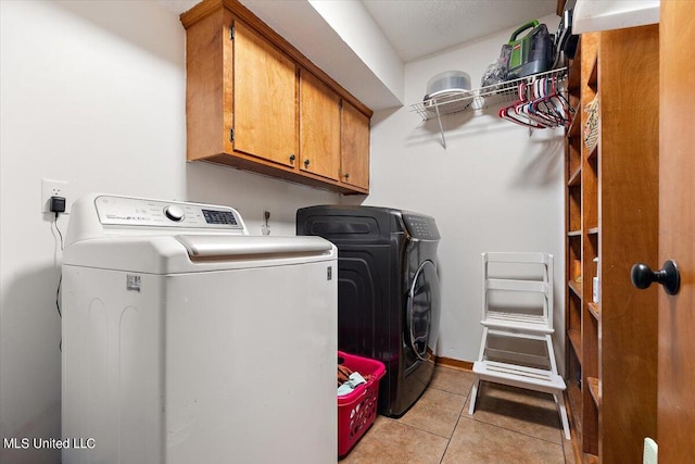 laundry room featuring light tile patterned floors, washing machine and dryer, and cabinets