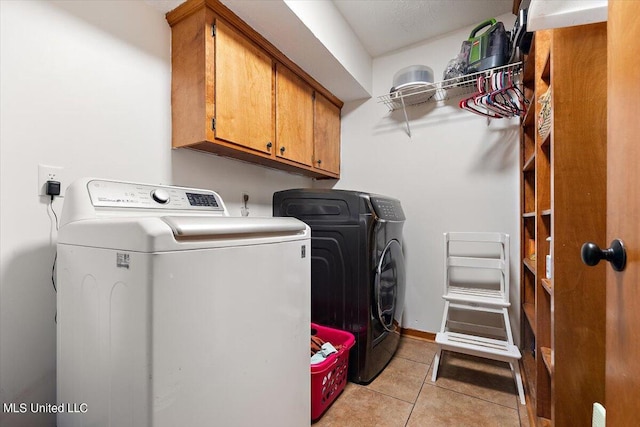 laundry area featuring light tile patterned flooring, cabinet space, and washing machine and dryer