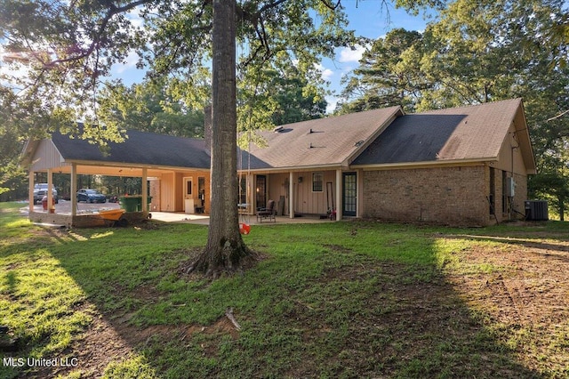 rear view of property with brick siding, cooling unit, a yard, and a patio area