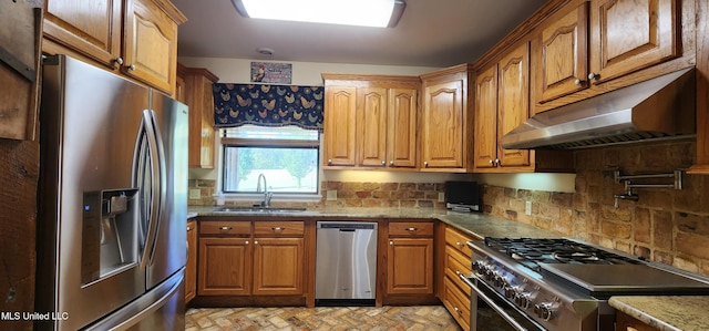 kitchen with stone counters, appliances with stainless steel finishes, sink, and decorative backsplash