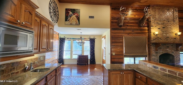 kitchen with a wealth of natural light, sink, stainless steel microwave, and a chandelier