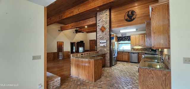 kitchen with beam ceiling, kitchen peninsula, stainless steel appliances, sink, and ceiling fan